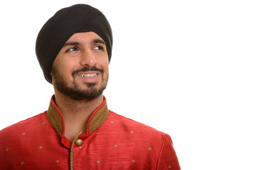 Young happy Indian Sikh thinking while wearing traditional cloth