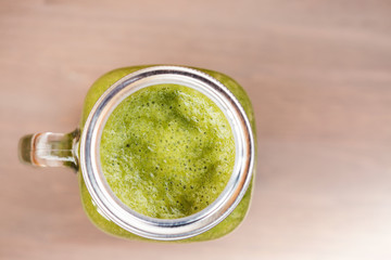 A green smoothie in a mason jar on wooden background