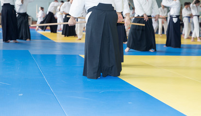 Fototapeta premium People in kimono practice Aikido with wooden jo on martial arts weapon training seminar