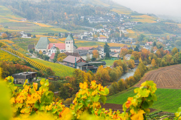 Picturesque autumnal view on Novacella, Varna, Bolzano in South Tyrol. Mountain scenery in Northern Italy. View from the top on the mountain valley. Colourful vineyards and yellow foliage on trees. - obrazy, fototapety, plakaty