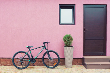 bike near the wall with a doorway and a window, part of the pavement