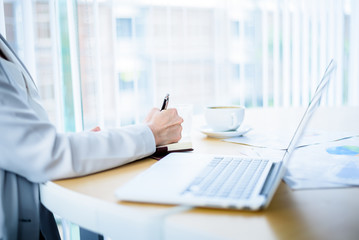 Business Woman Hand Working on Desktop table with Laptop , Document Papers , Coffee Cup and Smartphone