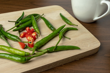 Green and red chili is a small piece on wooden floor.