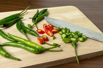 Green and red chili is a small piece on wooden floor.