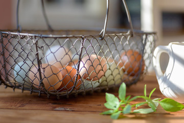 Closeup of rustic wire basket of fresh eggs on the table