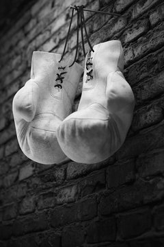 Old white boxing gloves hang on nail on brick wall with copy space for text. High resolution 3d render