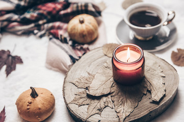 Cozy Autumn seasonal concept, candle, cup hot black tea coffee Fall fallen maple leaves. vintage style