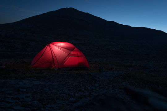 Illuminated red tent during the night on mountains
