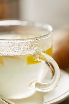 Transparent glass of hot tea with lemon, honey and ginger root i
