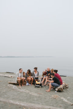 Multi generational family hanging out together around fire on the beach