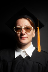 Portrait of Female bachelor in Black mantle and Graduation Cap with sunglasses