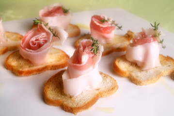 Italian food recipes spiced with herbs Colonnata lard rolls on toasted bread slices.