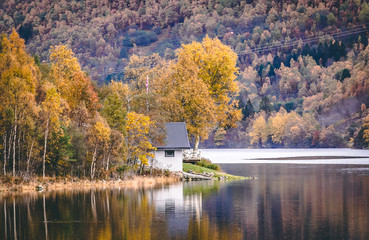 small house at mountain lake in Norway in autumn