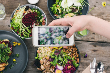young woman in a cafe, photographing food with her phone