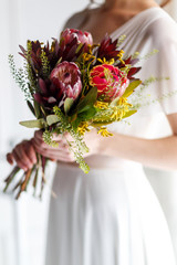 Happy bride in a white dress with a beautiful bouquet in her hands, close-up