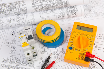 Electrical engineering drawings, insulating tape, modular circuit breaker and digital multimeter.