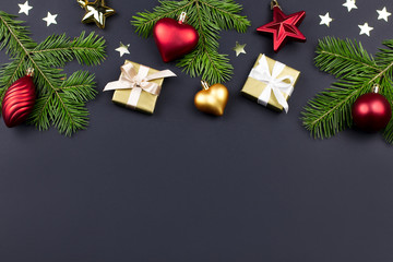 Festive Christmas background with fir branches, giftboxes, red decorations on black, copy space