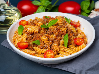 Bolognese pasta. Fusilli with tomato sauce, ground minced beef, basil leaves. Traditional italian cuisine. Side view