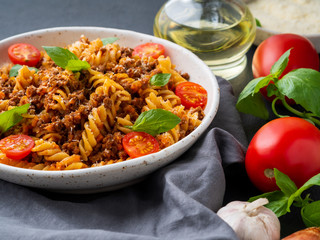 Bolognese pasta. Fusilli with tomato sauce, ground minced beef, basil leaves. Traditional italian cuisine. Side view