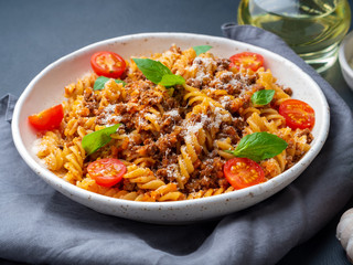 Bolognese pasta. Fusilli with tomato sauce, ground minced beef, basil leaves. Traditional italian cuisine. Side view