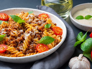 Bolognese pasta. Fusilli with tomato sauce, ground minced beef, basil leaves. Traditional italian cuisine. Side view