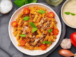 Bolognese pasta. Fusilli with tomato sauce, ground minced beef, basil leaves. Traditional italian cuisine. Top view