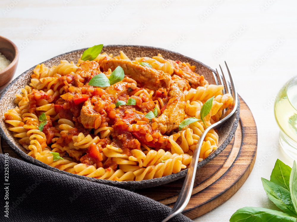 Wall mural fusilli pasta with tomato sauce, chicken fillet with basil leaves on light white wooden background, side view