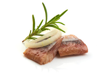 Pieces of salted herring fillet with onion ring and herbs, isolated on a white background. Close-up.
