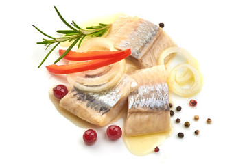 Pieces of salted herring fillet with onion ring, pepper and herbs, isolated on a white background.