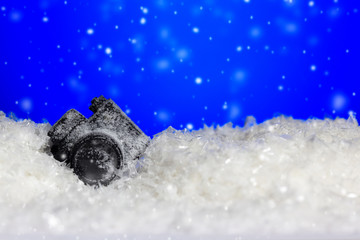 Frozen DSLR camera on blue background with copy space