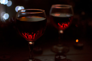 Glasses with red wine. Garlands in the background.
