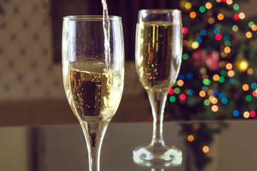 New Year's Eve. Two glasses on the table. Champagne pouring into a glass