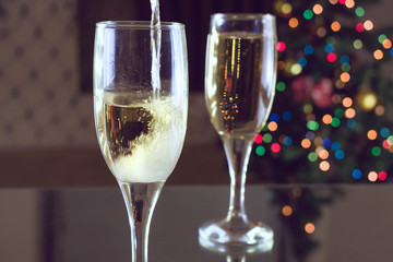 New Year's Eve. Two glasses on the table. Champagne pouring into a glass