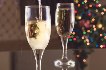 New Year's Eve. Two glasses on the table. Champagne pouring into a glass