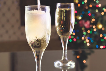 New Year's Eve. Two glasses on the table. Champagne pouring into a glass