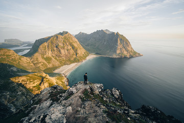 Man standing on mountain peak over water, Norway