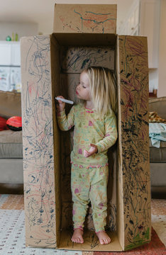 Child Playing with Box and Writing on it