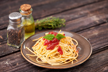 spaghetti with ketchup and Basil on dark wooden background