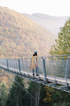 Young woman walking on a long bridge in nature