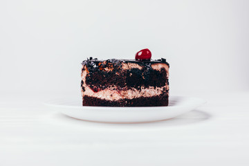 Piece of chocolate cake with crumbs and cherry
