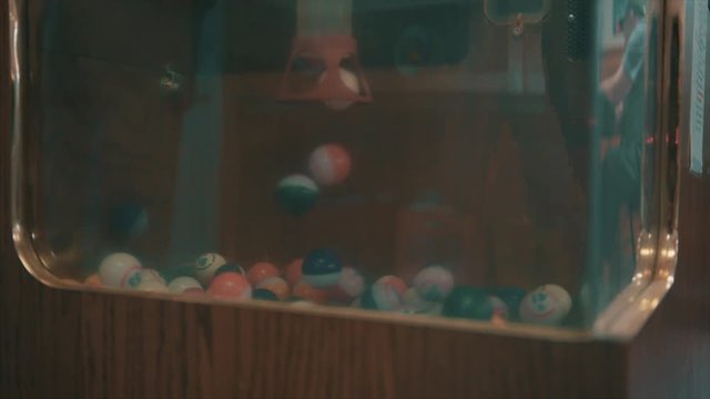 Bingo balls float and fall in slow motion at an aged bingo hall.