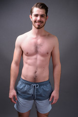 Fototapeta premium Young handsome bearded man shirtless against gray background