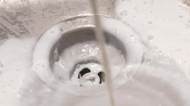 Milk Is Spilled Into A Kitchen Sink And Runs Down The Drain