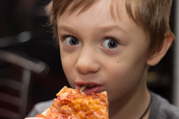 The boy eats a very tasty pizza with great pleasure.