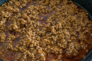 Close-up of minced meat with tomato sauce in the pan. Prepared for spaghetti Bolognese