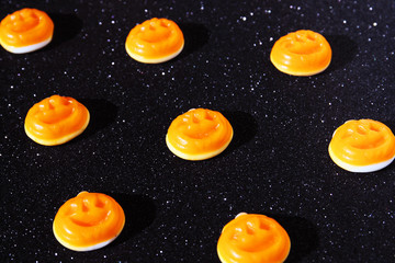 Jack-O-'Lantern Halloween candy on a sparkly black background.