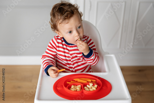 Baby In High Chair Eating Finger Food Stockfotos Und