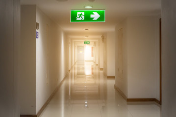 green emergency exit sign in hotel showing the way to escape - obrazy, fototapety, plakaty