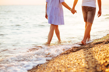 Young happy couple on seashore in the lights of sunset.