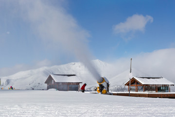 A snow cannon pours extra snow onto the ski track